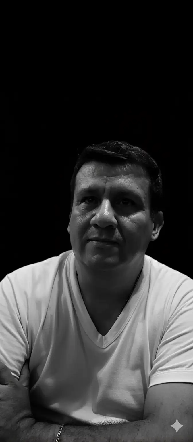 Retrato intenso, hiperrealista y en primer plano en blanco y negro, con iluminación cinematográfica lateral de alto contraste que resalta los rasgos faciales, creando sombras impactantes. El sujeto mantiene una mirada firme y segura hacia arriba, dirigida hacia un vacío oscuro. El entorno irradia misterio, realzado por un fondo minimalista completamente negro. Cada detalle aparece en resolución 4K, preservando fielmente la estructura facial, la textura del cabello y la autenticidad de la fotografía original.